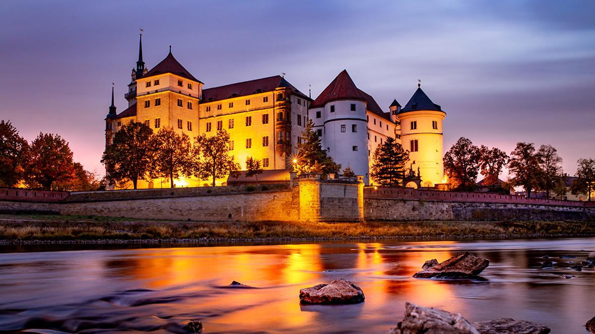 Das Schloss im Sonnenuntergang, im Vordergrund die Elbe