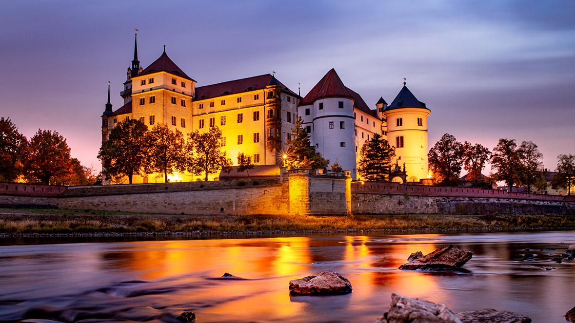Das Schloss im Sonnenuntergang, im Vordergrund die Elbe